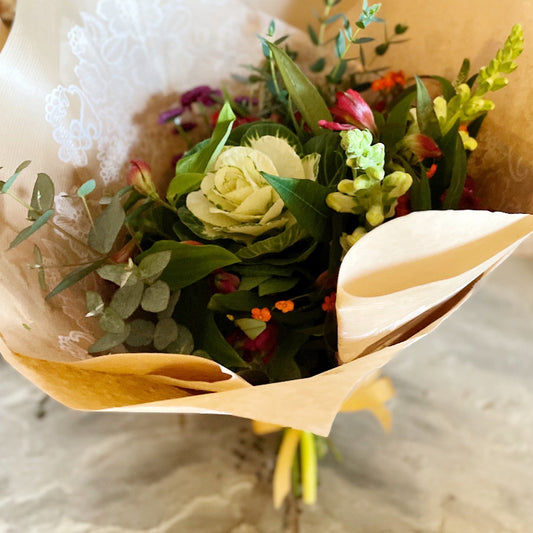 Bouquet of flowers wrapped in brown paper on a textured surface