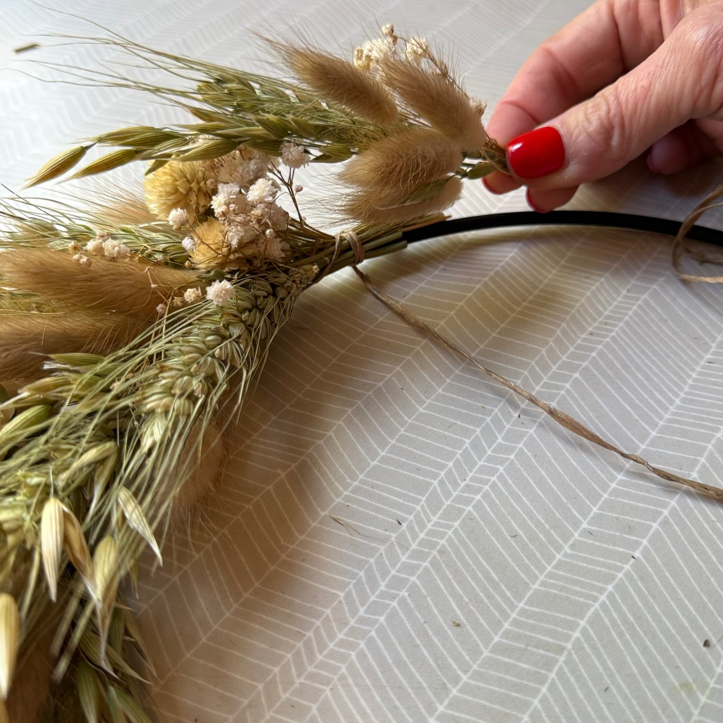 Hand arranging dried plants on a wreath