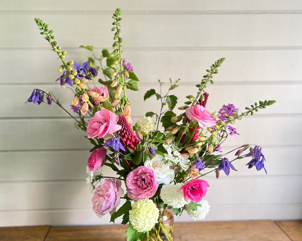 A wild,  asymmetrical floral design in seasonal May flowers including Roses, Ranunculus, Viburnum, Lupin and Foxgloves.