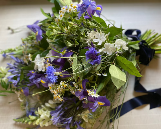 A Cottage garden inspired, foam free floral tribute containing Iris, Cornflowers, Phlox, Snapdragons and Agapanthus.