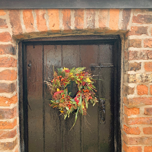 Decorative Autumnal wreath on a black door of a brick building