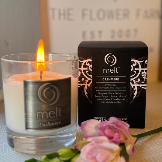 Melt Cashmere candle and packaging with flowers on a table sold by Flower Farm Floristry.
