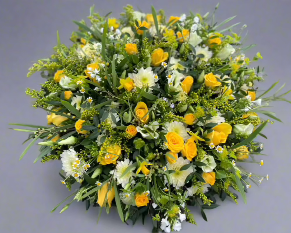 A large funeral posy of yellow and cream flowers. including Roses, Daffodils, Chrysanthemums and Lisianthus.