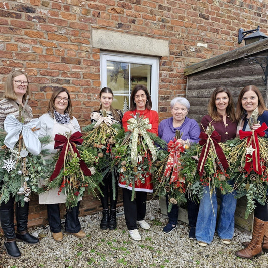 A group shot of a fabulous Christmas door swag workshop with Flower Farm Floristry, created in fresh materials with beautiful bows.