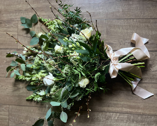 A mixed selection of white and cream flowers with lots of foliage including Eucalyptus.