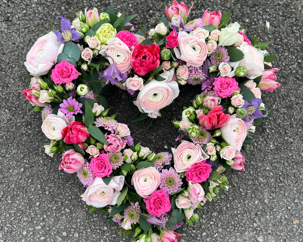 A pretty heart shaped tribute of Spring flowers and Roses.