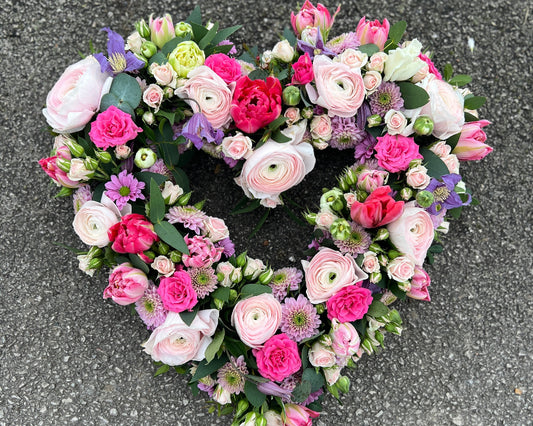 A pretty heart shaped tribute of Spring flowers and Roses.