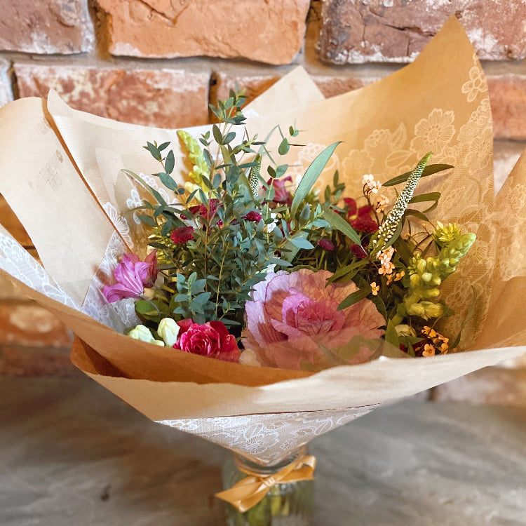Bouquet of flowers wrapped in brown paper.