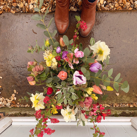 Colourful bouquet of Spring flowers on a stone floor with brown boots in the background
