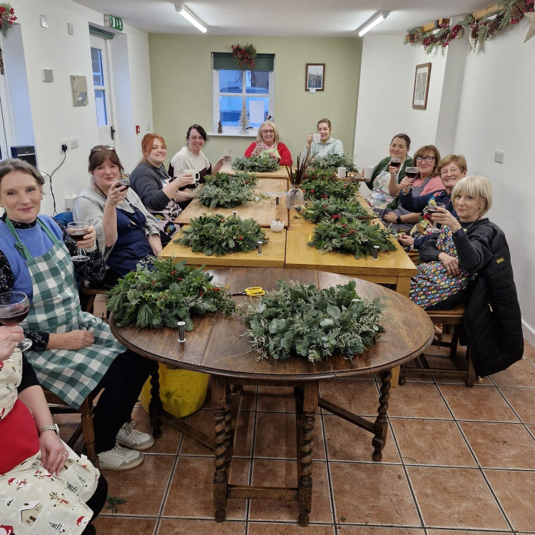 Group of people making wreaths and enjoying a glass of mulled wine at The Farm, Burscough