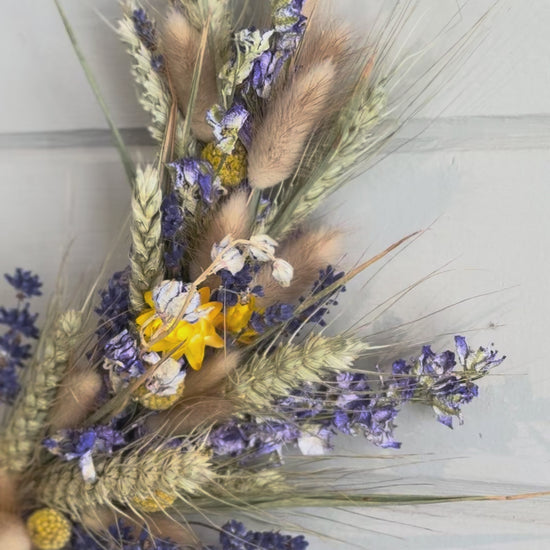 blue and yellow dried flowers arranged around a black ring