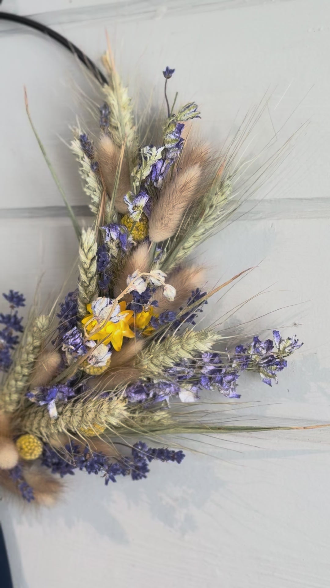 blue and yellow dried flowers arranged around a black ring